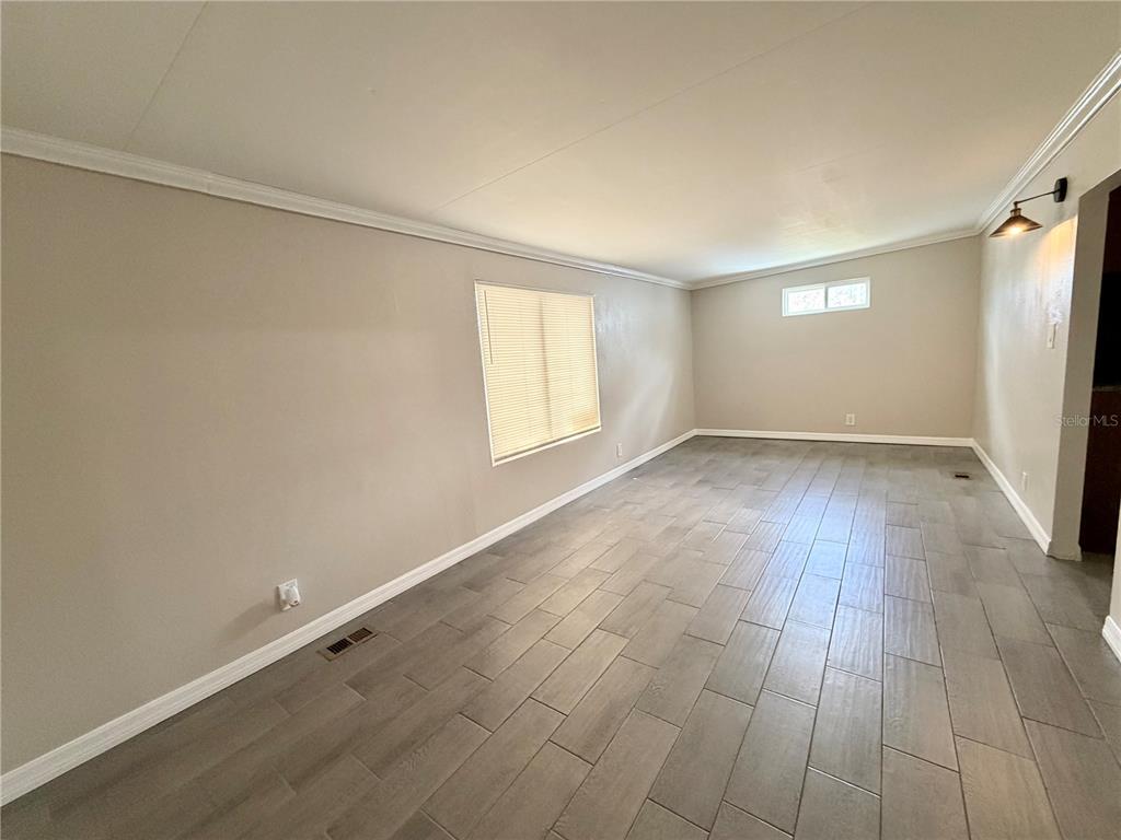 7037 Lofty Drive Port Richey, FL 34668 - Photo 3 of 9 an empty room with wooden floor and windows