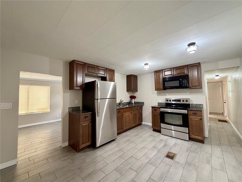 7037 Lofty Drive Port Richey, FL 34668 - Photo 4 of 9 a kitchen with stainless steel appliances granite countertop a refrigerator stove and oven