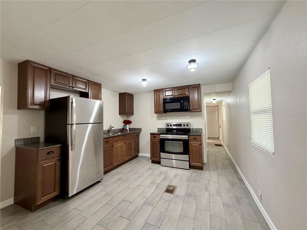 7037 Lofty Drive Port Richey, FL 34668 - Photo 5 of 9 a kitchen with stainless steel appliances granite countertop a refrigerator microwave and sink