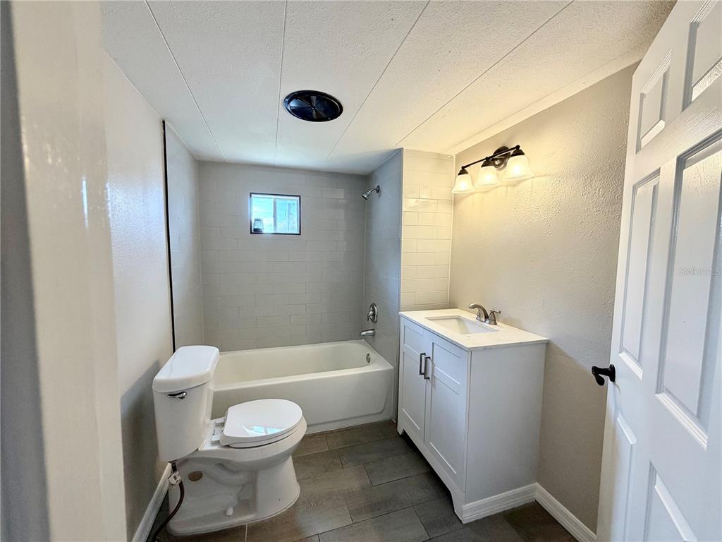 7037 Lofty Drive Port Richey, FL 34668 - Photo 7 of 9 a bathroom with a toilet sink vanity tub and shower