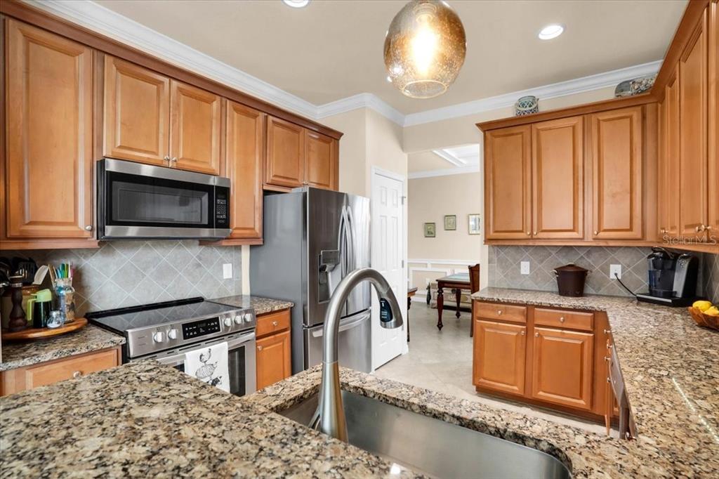 20201 Ragazza Circle, Unit 201 Venice, FL 34293 - Photo 24 of 58 a kitchen with stainless steel appliances granite countertop a stove top oven a sink dishwasher a dining table and chairs with wooden floor