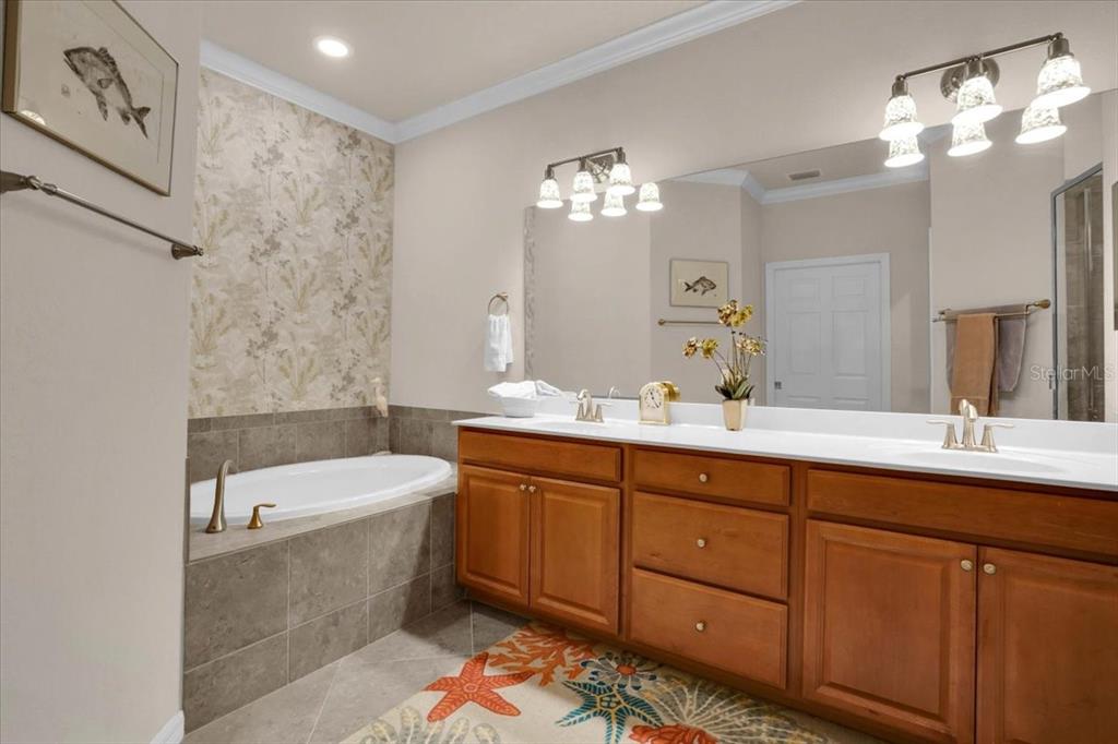 20201 Ragazza Circle, Unit 201 Venice, FL 34293 - Photo 33 of 58 a bathroom with a double vanity sink large mirror and a bathtub