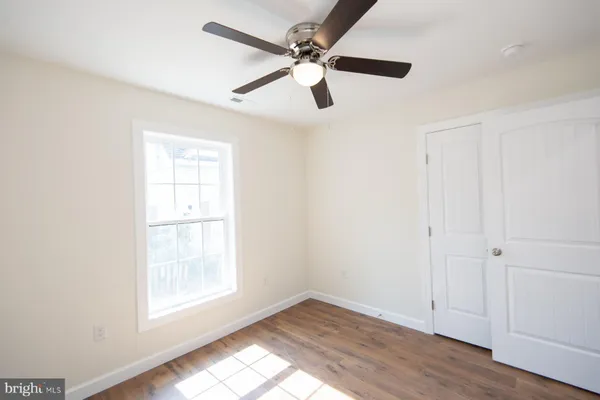 an empty room with wooden floor ceiling fan and windows
