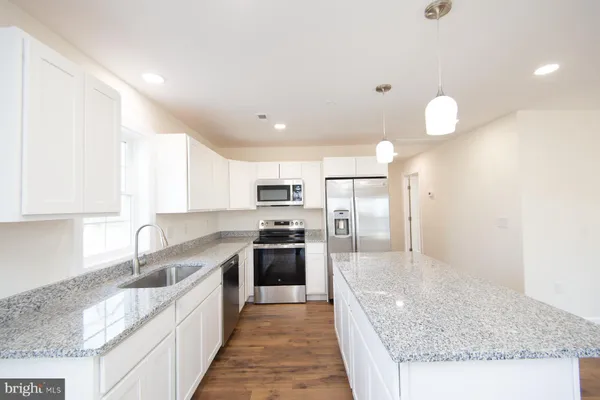a large kitchen with granite countertop a sink counter space stainless steel appliances and cabinets