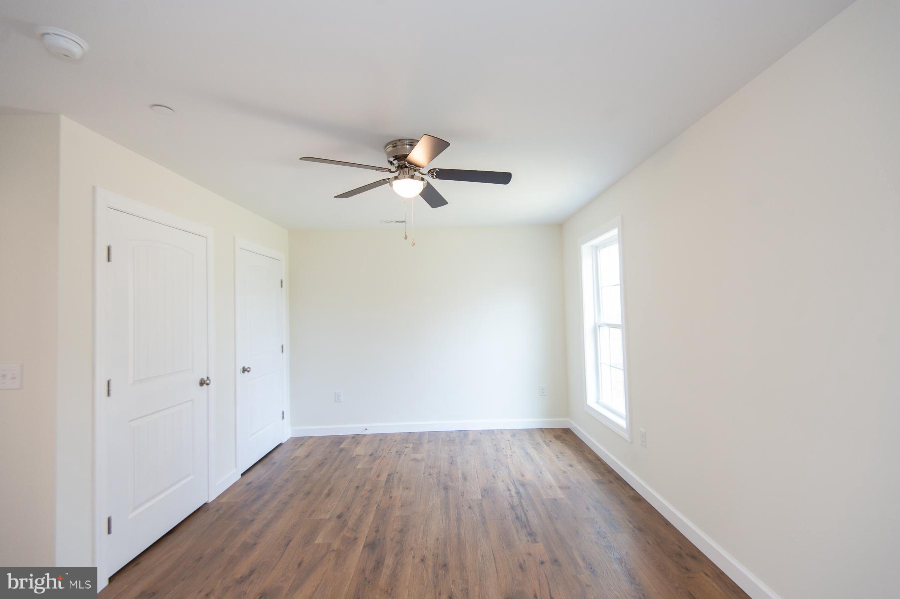 406 Charles Street Hurlock, MD 21643 - Photo 8 of 17 an empty room with wooden floor fan and windows