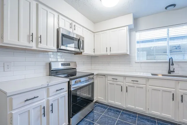 a kitchen with white cabinets stainless steel appliances and sink