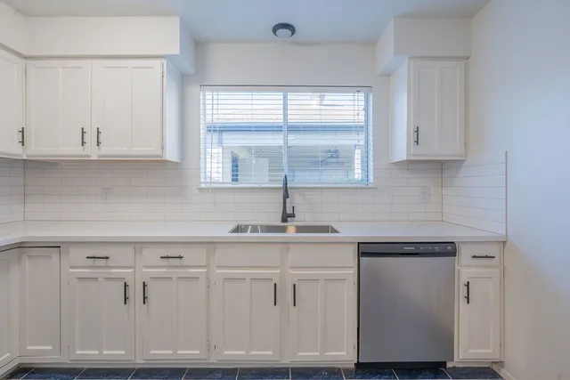 a kitchen with white cabinets and sink