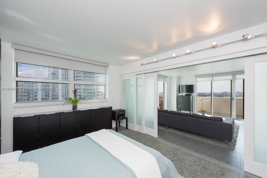 90 Alton Road, Unit 1502 Miami Beach, FL 33139 - Photo 15 of 29 a bedroom with a bed and glass window