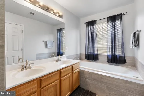 a bathroom with double vanity sinks and a bathtub