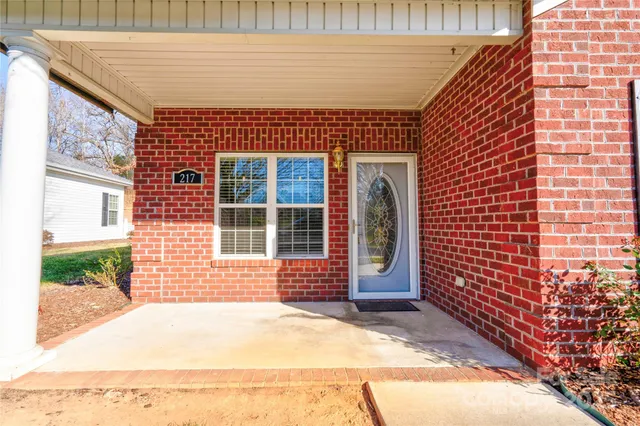a view of a white house with a large tree and many windows