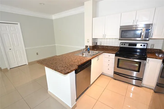a kitchen with granite countertop a sink stove and microwave
