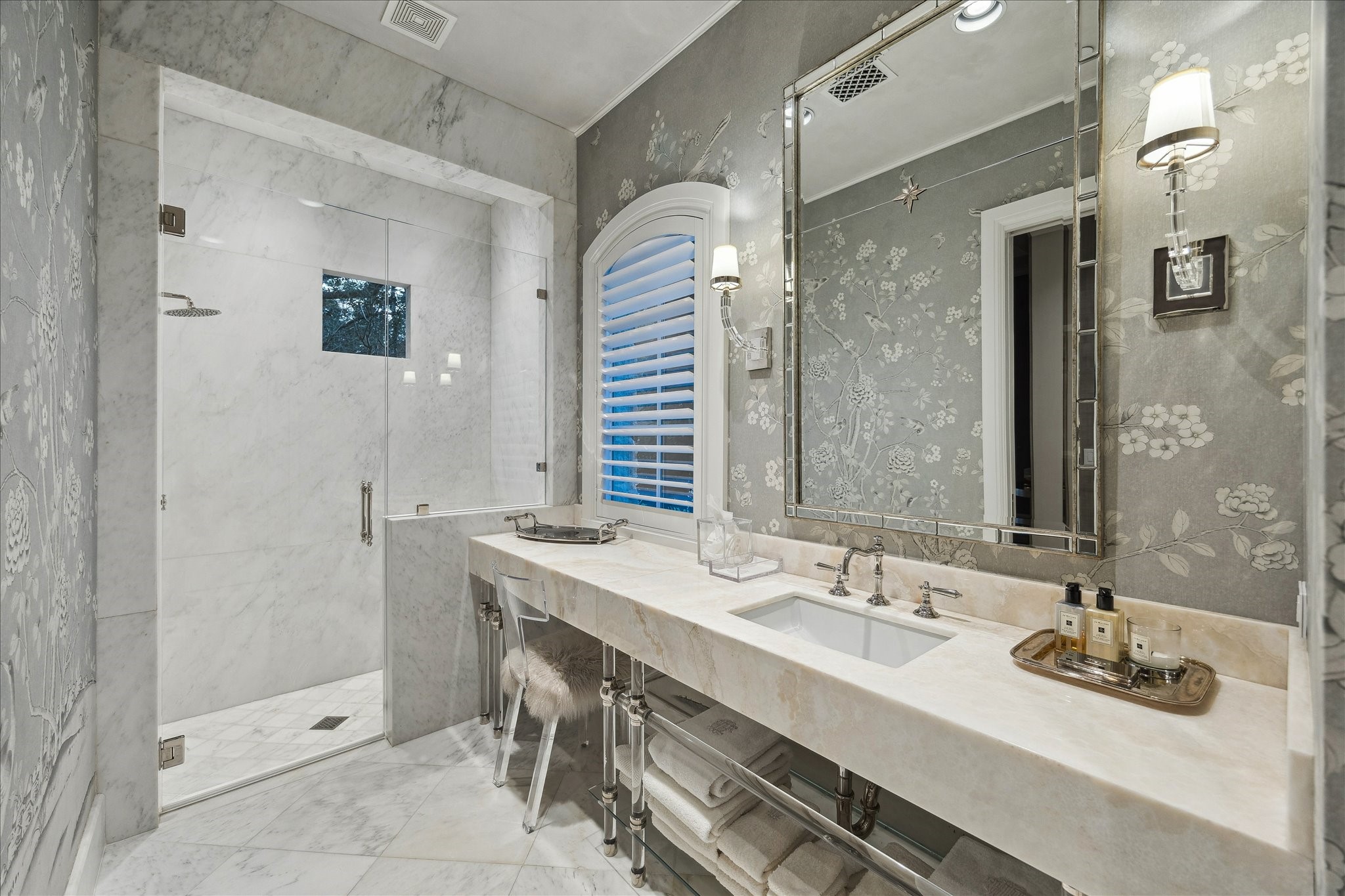 220 Merrie Way Lane Houston, TX 77024 - Photo 29 of 50 Hand-painted Gracie wallpaper & marble flooring set a refined tone in this guest bath. The marble-topped acrylic vanity is framed by a designer mirror and polished nickel sconces. A walk-in shower features single-slab marble walls, a marble bench, and polished nickel fixtures, while the separate water closet continues the Gracie wallpaper with a Toto toilet.