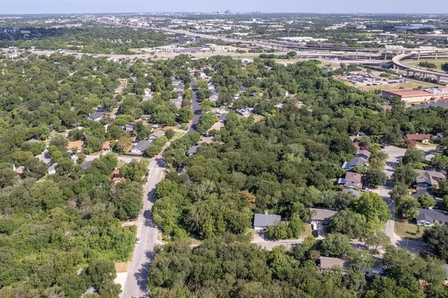 an aerial view of residential houses with outdoor space and trees