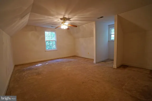 an empty room with windows and chandelier fan