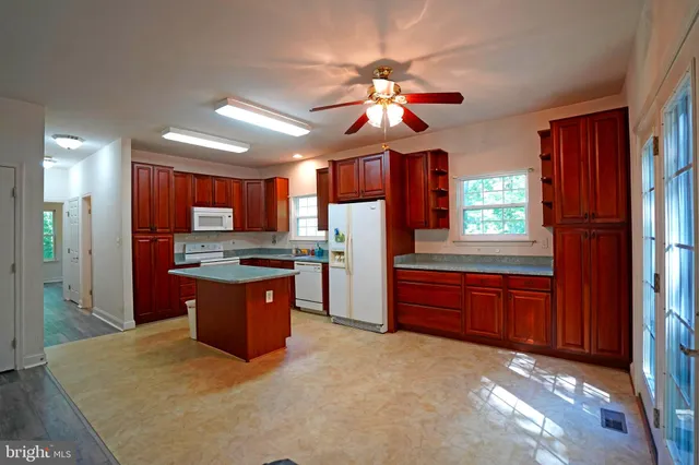 a large kitchen with stainless steel appliances granite countertop a refrigerator a sink dishwasher a dining table and chairs with wooden floor