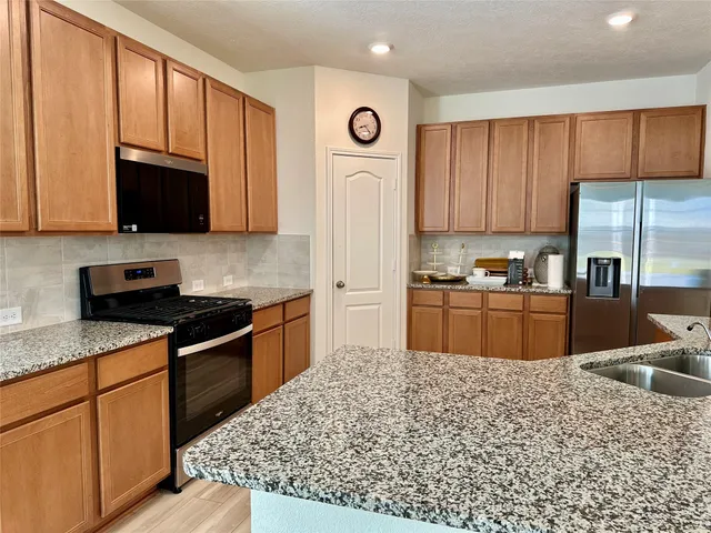 a kitchen with stainless steel appliances granite countertop a stove refrigerator sink and cabinets