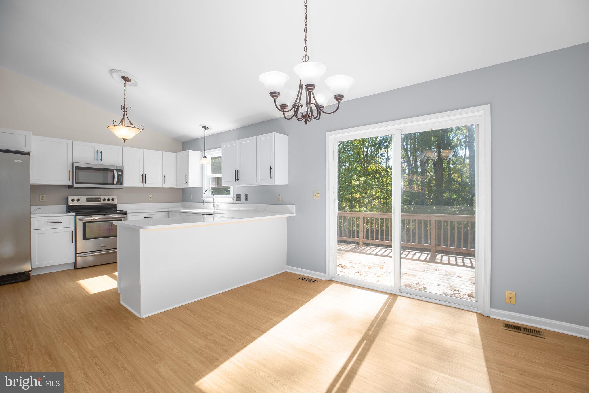 8 Rutledge Cove Ruther Glen, VA 22546 - Photo 13 of 46 a open kitchen with kitchen island a stove a refrigerator a sink dishwasher with a dining table and chairs with wooden floor