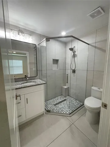 a bathroom with a granite countertop sink toilet a mirror and shower