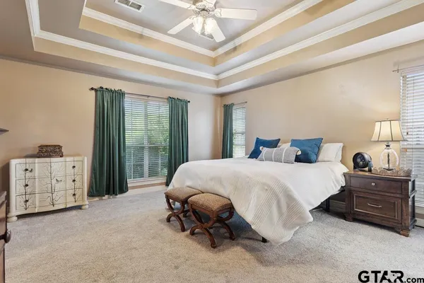 a spacious bedroom with a bed a dresser and a chandelier