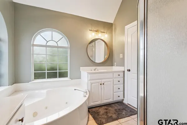 a bathroom with a bathtub a mirror a sink and a window