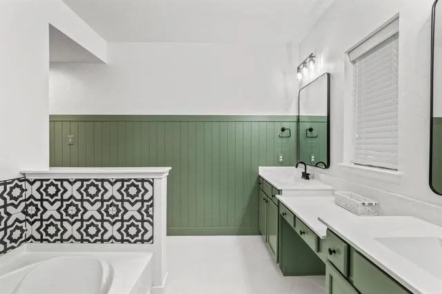 a bathroom with a double vanity sink mirror and a bathtub