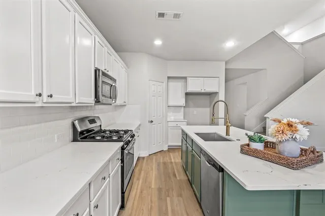 a kitchen with stainless steel appliances a sink a stove and cabinets