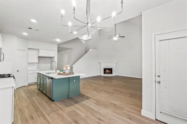 a kitchen with stainless steel appliances a stove a sink and white cabinets with wooden floor