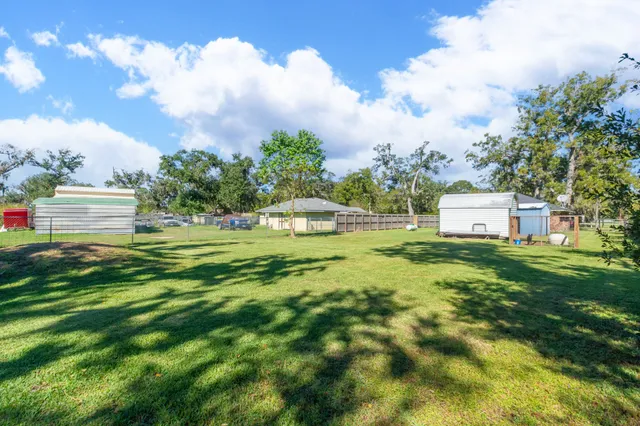a view of a big house with a big yard and large trees