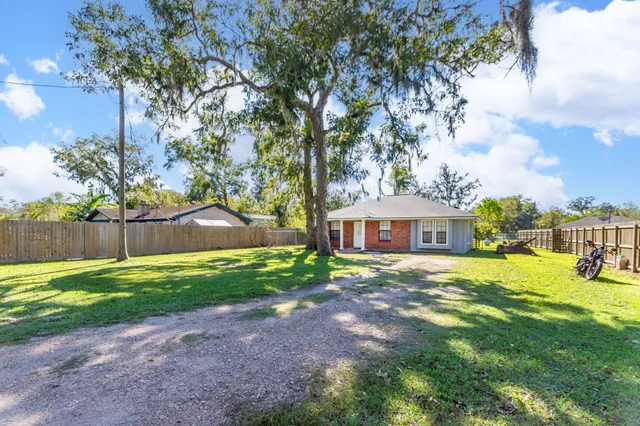 a view of a big house with a big yard and large trees