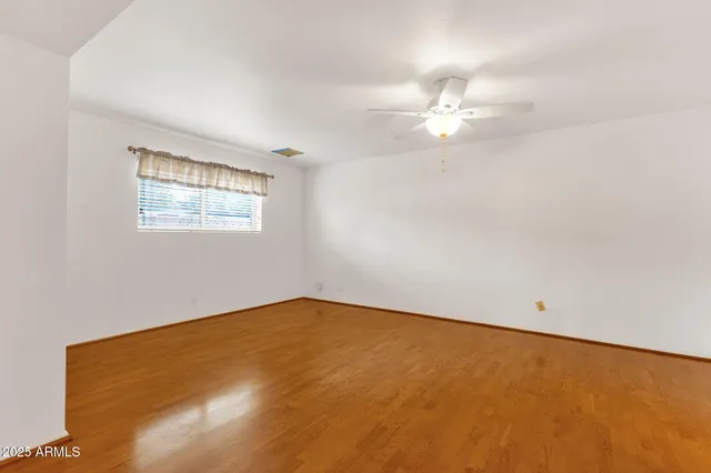 a spacious bedroom with a bed a window and dresser