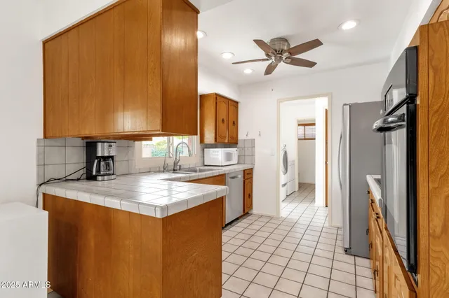 a kitchen with stainless steel appliances granite countertop a refrigerator a sink dishwasher a stove and white countertops with wooden floor