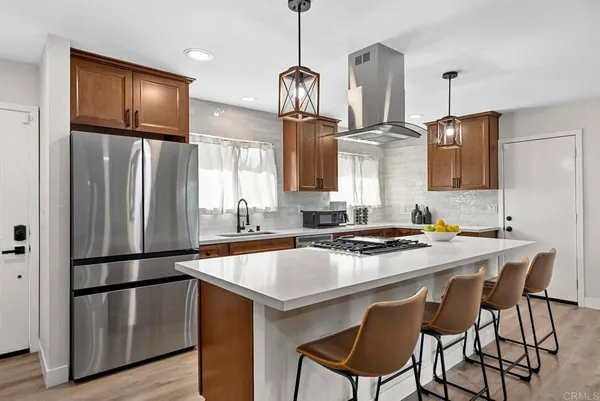 a kitchen with stainless steel appliances granite countertop a sink refrigerator a stove a dining table and chairs