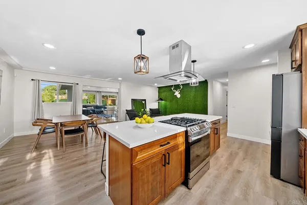 a kitchen with a stove a refrigerator a sink dishwasher with a dining table and chairs with wooden floor