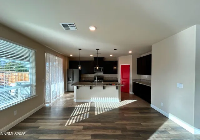 a kitchen with stainless steel appliances kitchen island granite countertop a refrigerator stove oven and white cabinets with wooden floor