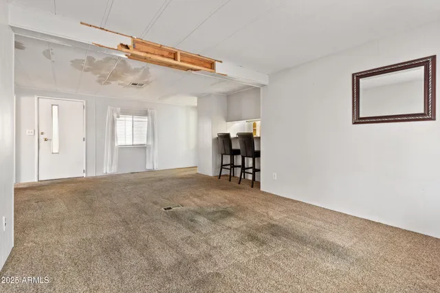 a view of an empty room with chandelier fan and windows