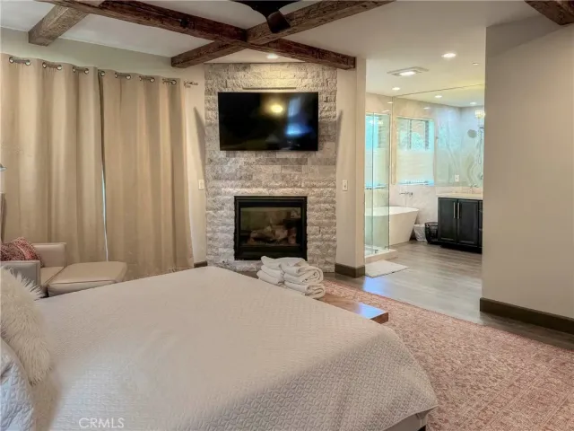 a large white bed sitting in a spacious bedroom next to a fireplace and a large window