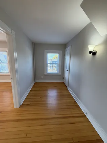 a view of an empty room with window and wooden floor