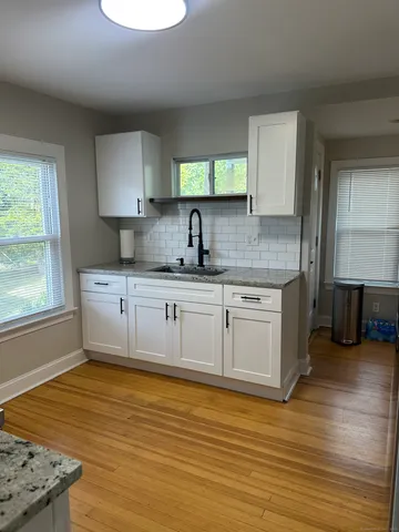a kitchen with stainless steel appliances granite countertop a sink cabinets and wooden floor