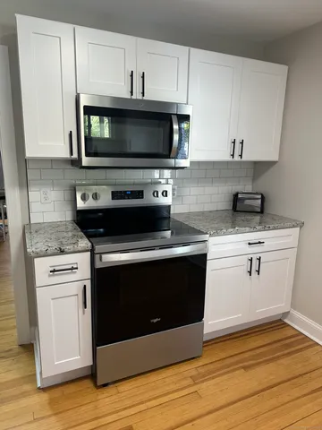 a kitchen with stainless steel appliances a stove a microwave a sink and cabinets