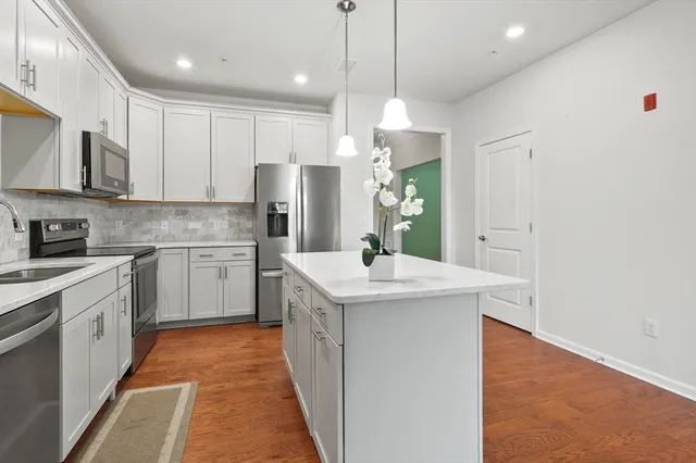 a kitchen with stainless steel appliances granite countertop a sink a stove a refrigerator and island with wooden floor