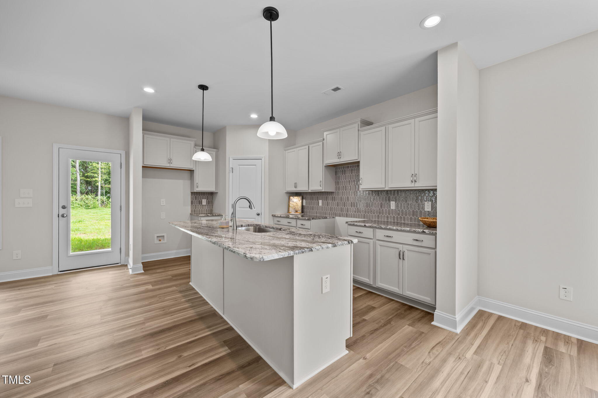 187 Regis Lane, Unit 10 Coats, NC 27521 - Photo 9 of 38 a kitchen with kitchen island granite countertop a sink cabinets and wooden floor
