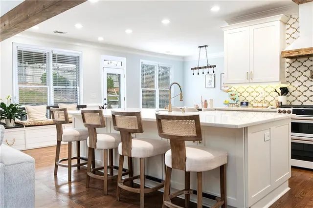 a dining hall with stainless steel appliances kitchen island granite countertop a table chairs and a sink
