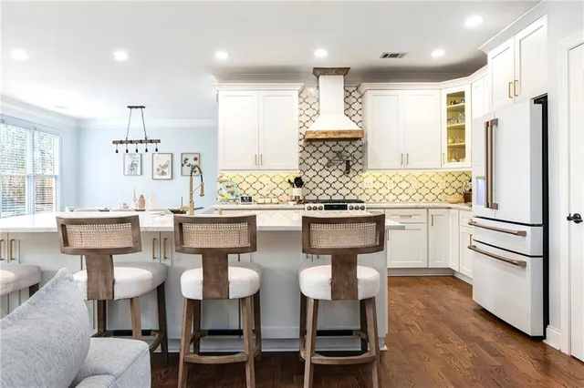 a kitchen with stainless steel appliances kitchen island granite countertop a table chairs stove and refrigerator