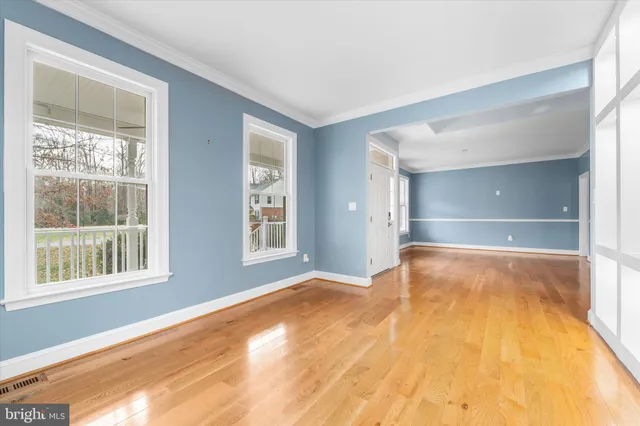 a view of an empty room with a window and wooden floor