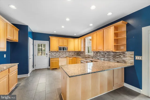 a large white kitchen with stainless steel appliances granite countertop a refrigerator and a stove