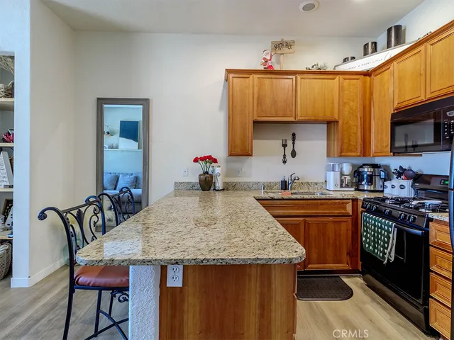 a kitchen with granite countertop a stove a sink dishwasher and cabinets with wooden floor