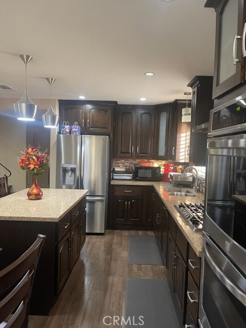 a kitchen with kitchen island stainless steel appliances a sink stove and refrigerator