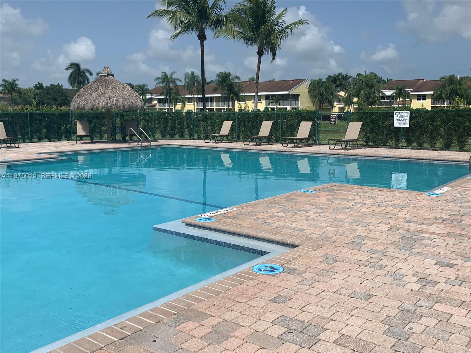 2211 Southeast 23rd Road, Unit 2211 Homestead, FL 33035 - Photo 28 of 39 a view of a swimming pool with a table and chairs
