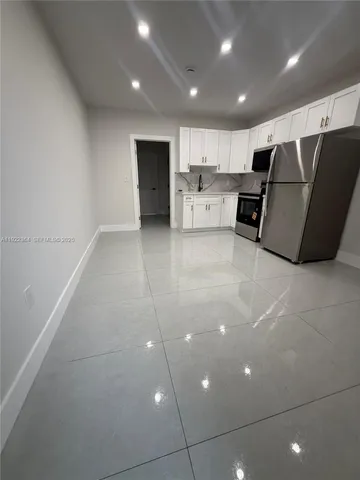 a large white kitchen with kitchen island granite countertop a refrigerator and a stove top oven