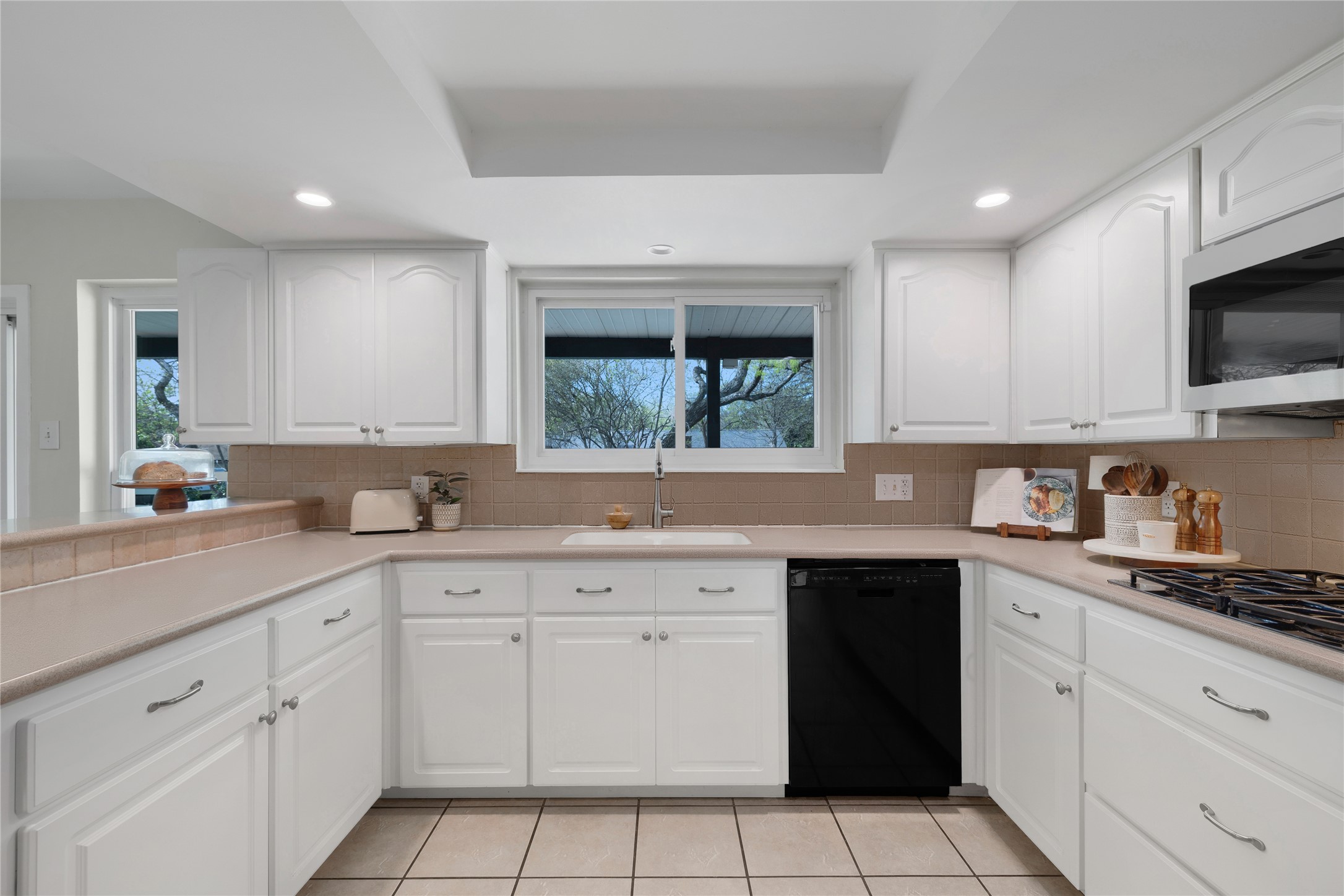 2403 Comburg Castle Way Austin, TX 78748 - Photo 18 of 40 Kitchen featuring dishwasher, light countertops, white cabinets, decorative backsplash, and recessed lighting